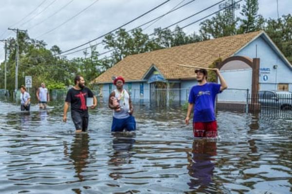 residents walk through a flooded street